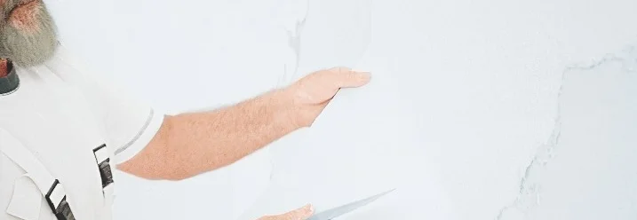 Person entfernt Tapetenreste von Wand